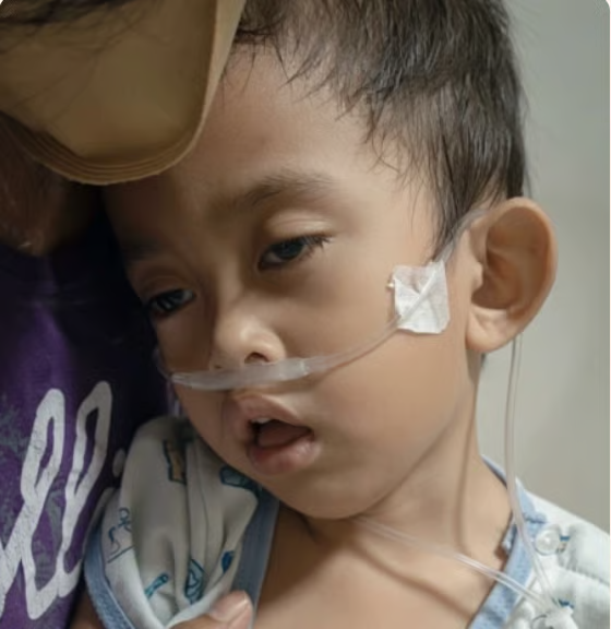 Pedro no colo da mãe, com o cateter de oxigênio no rosto